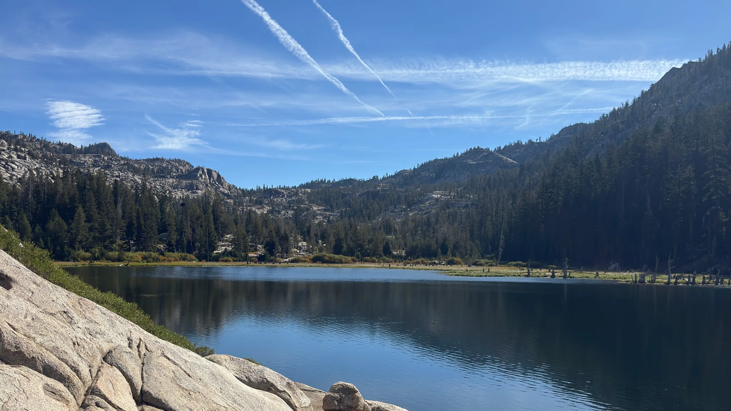 An alpine lake framed by granite and evergreen trees.
