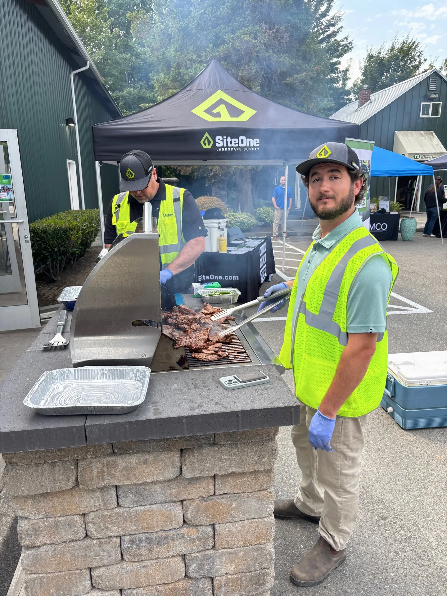 People at a grill beneath a SiteOne canopy at an outdoor event.