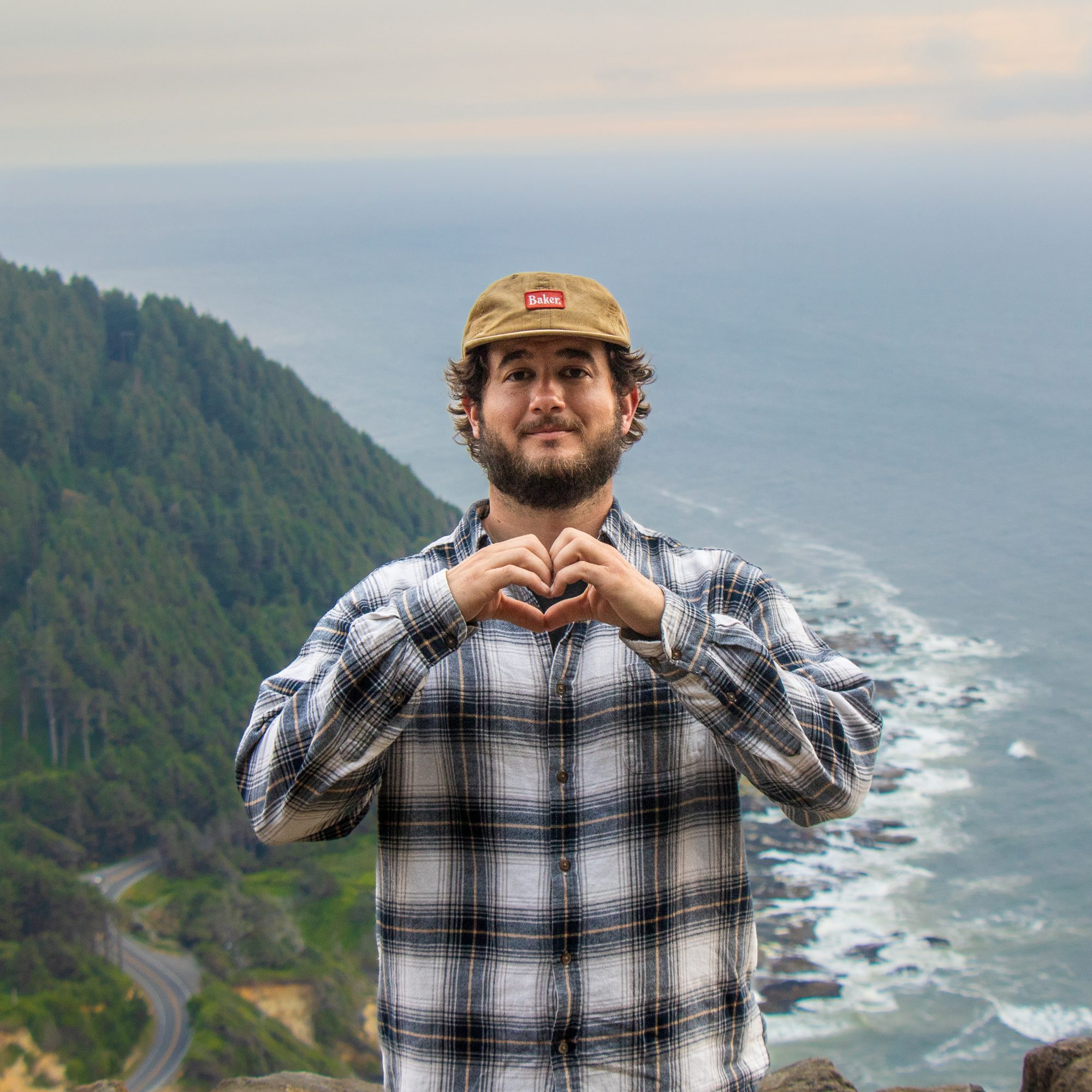 Alec making a heart with his hands at a coastal overlook
